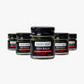 Multiple jars of Green Milk Pain Balm on a white background